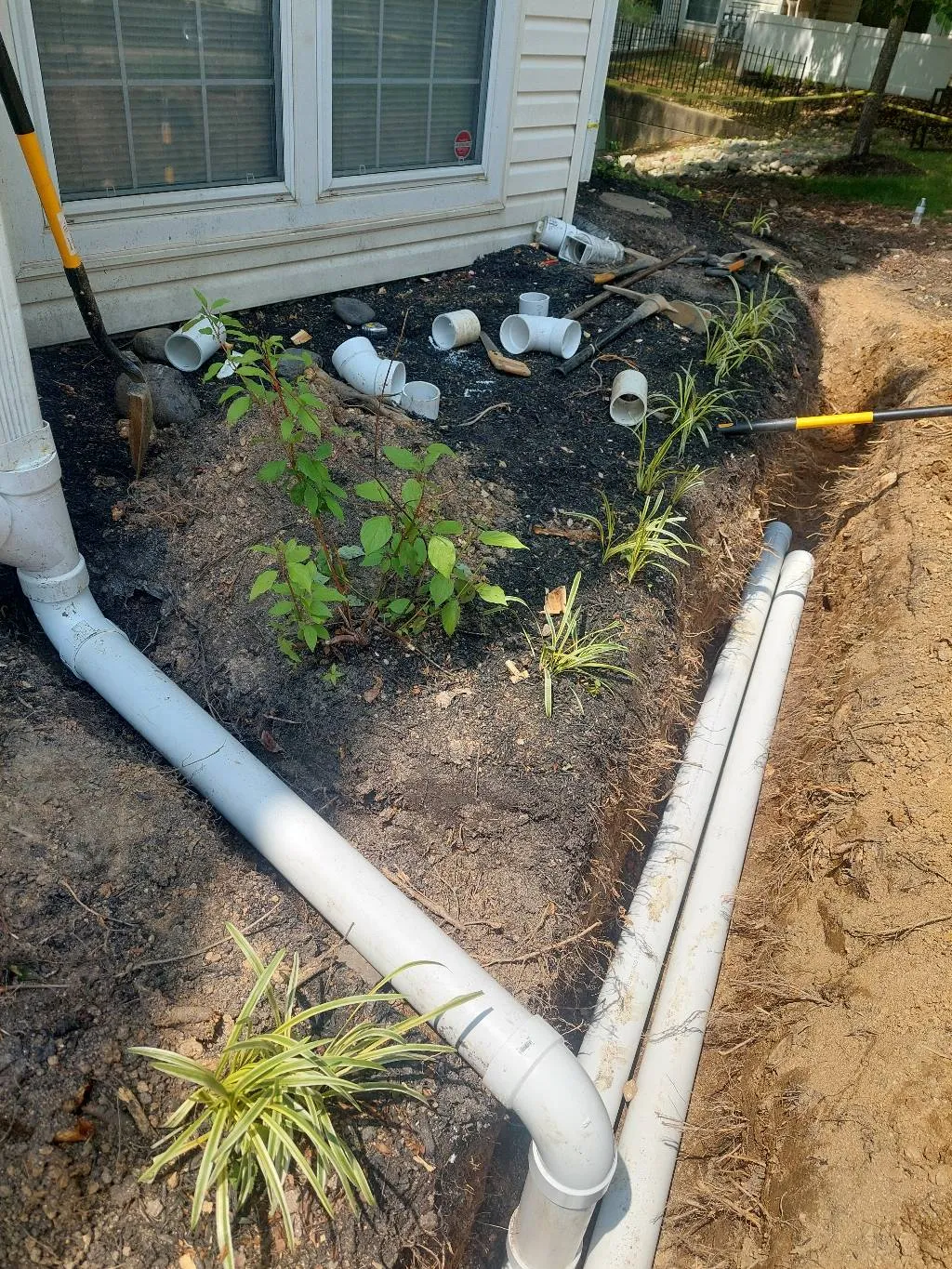 A downspout extension directing rainwater away from a home's foundation and into the yard