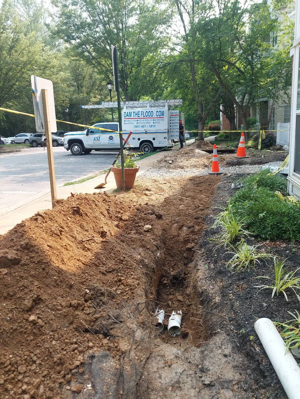 An exterior foundation drainage system being installed along the base of a home to redirect groundwater
